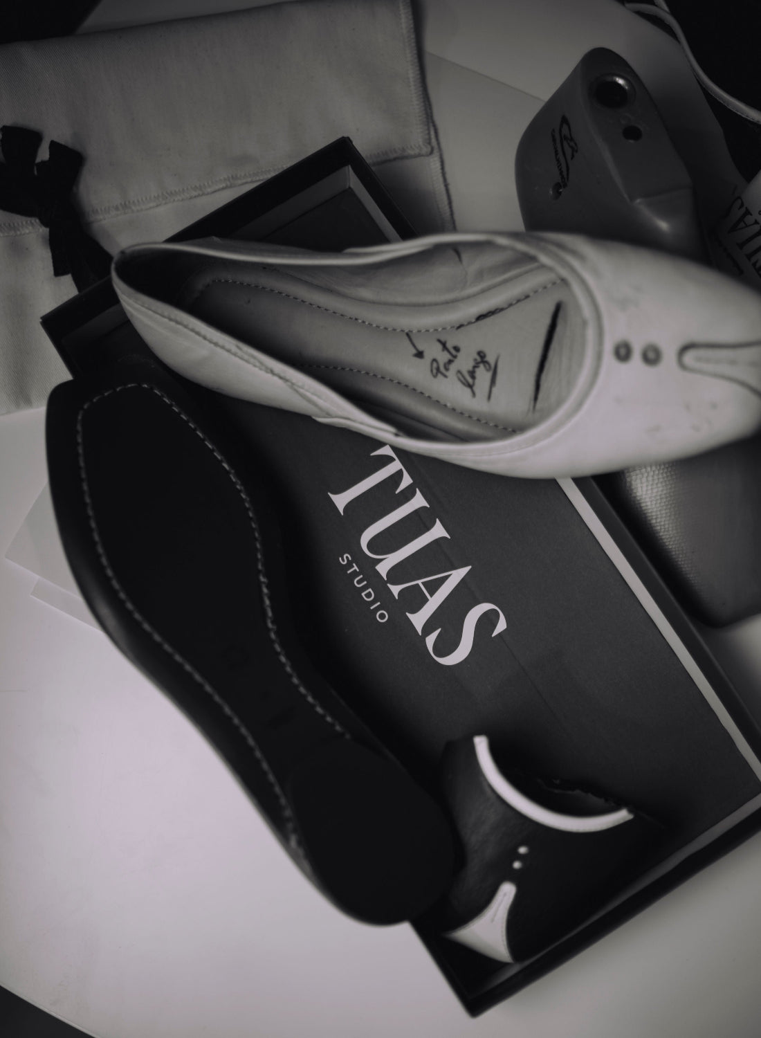 TUAS white flat shoes on a black box with 'TUAS STUDIO' branding