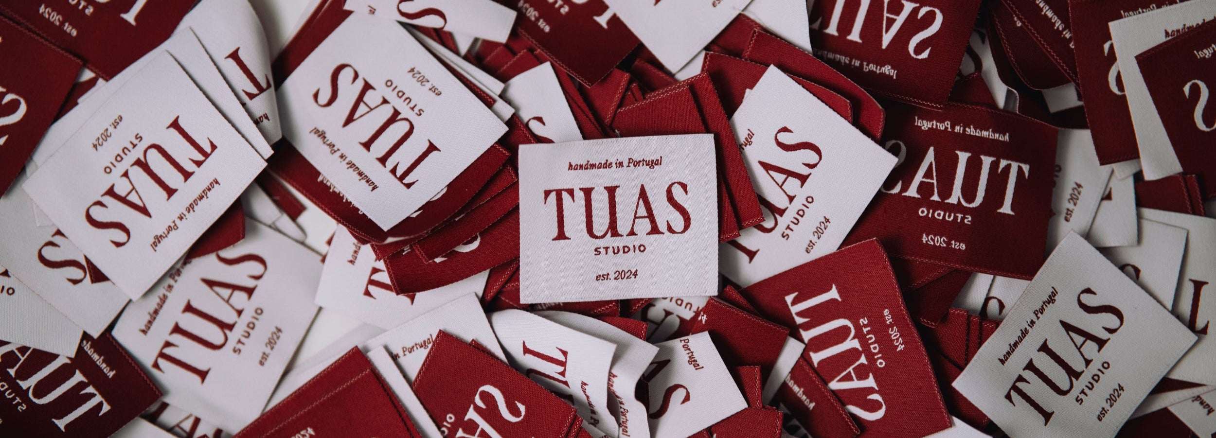 Collection of red and white 'TUAS' branded stickers scattered on a white background