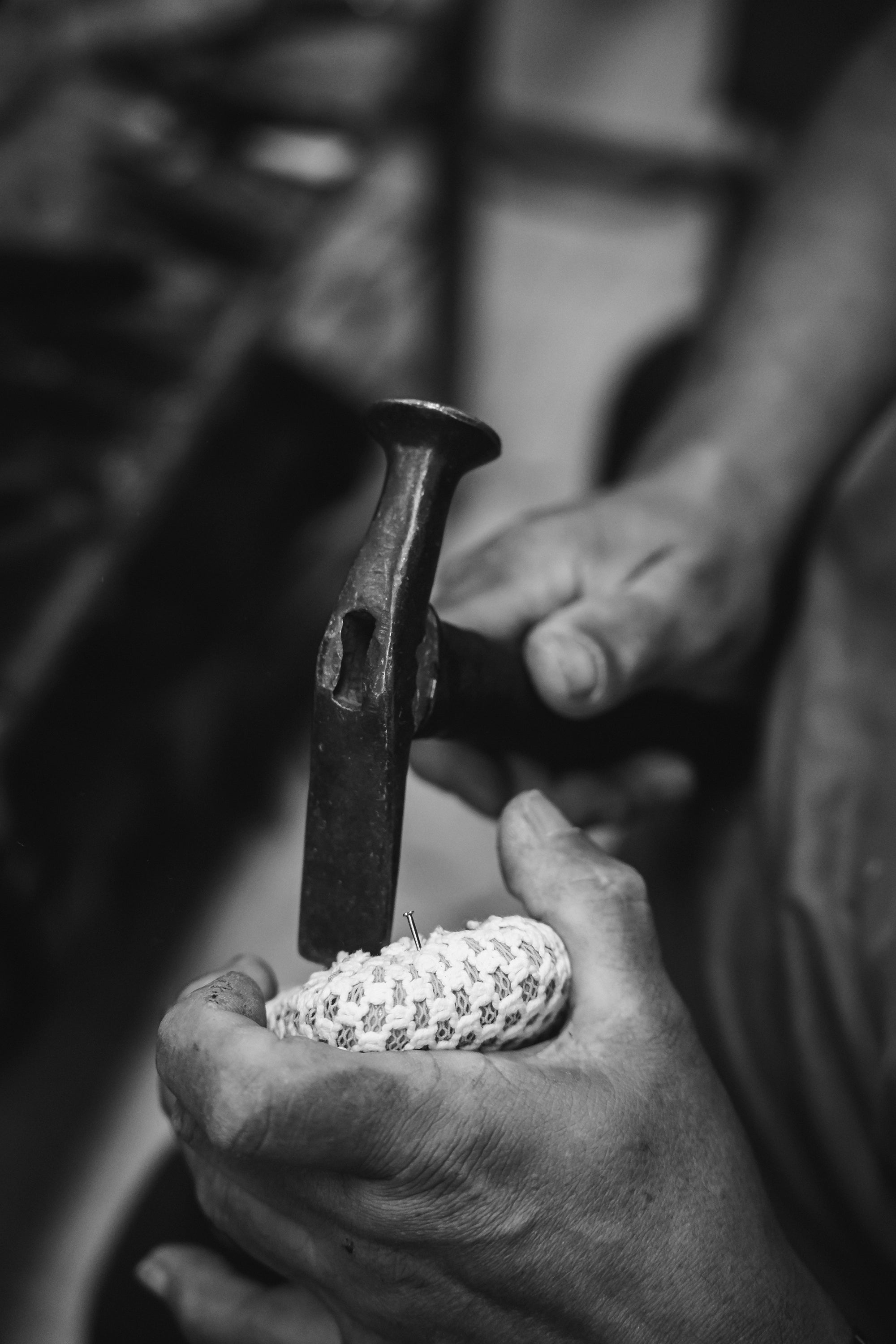 Person using a hammer on a small object with a blurred background