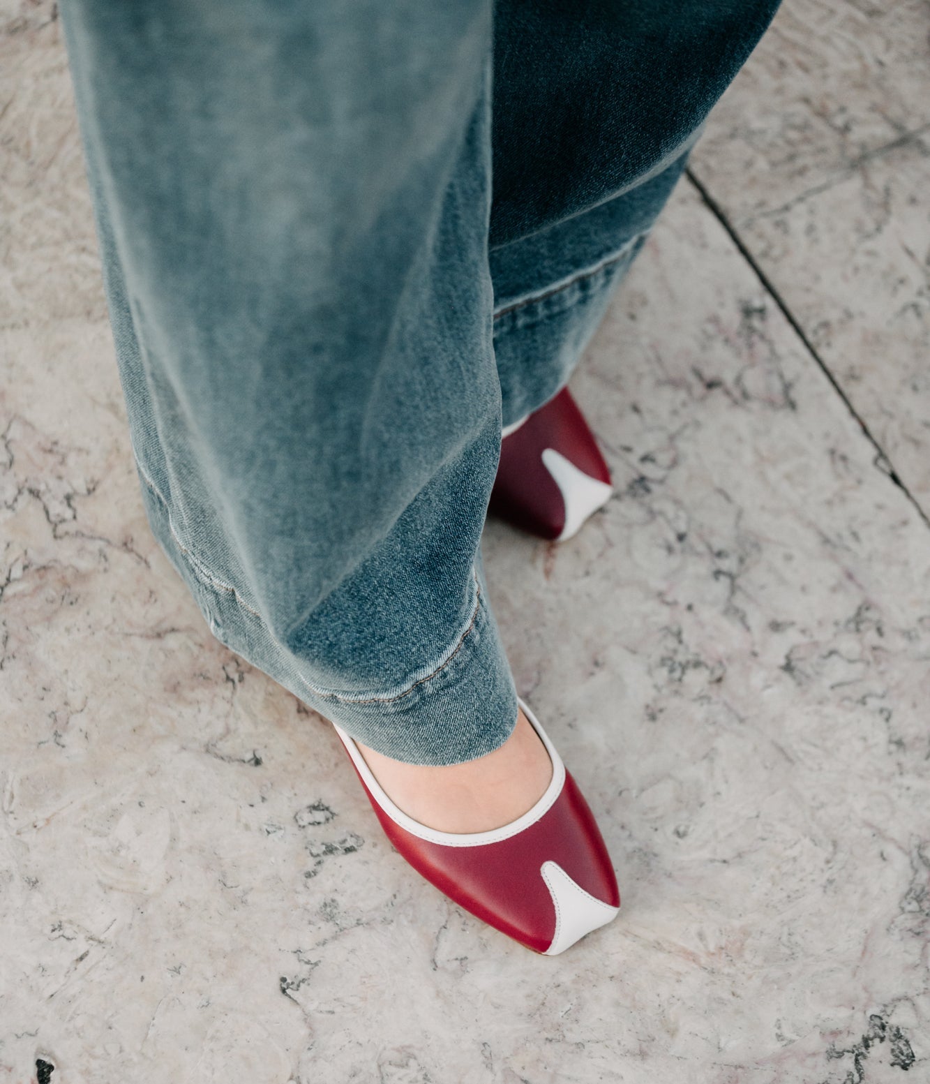 TUAS red flat shoes with white soles worn with blue jeans on a concrete surface