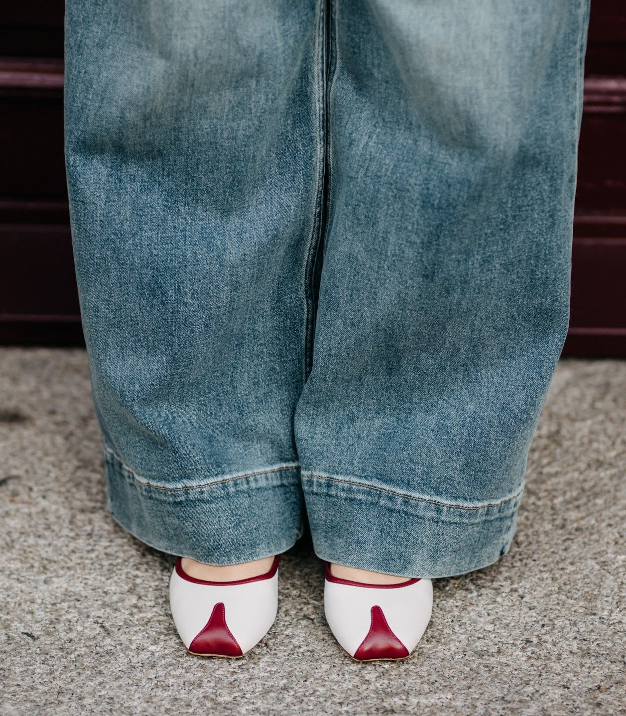 Person wearing blue jeans and white shoes with red accents on a neutral background