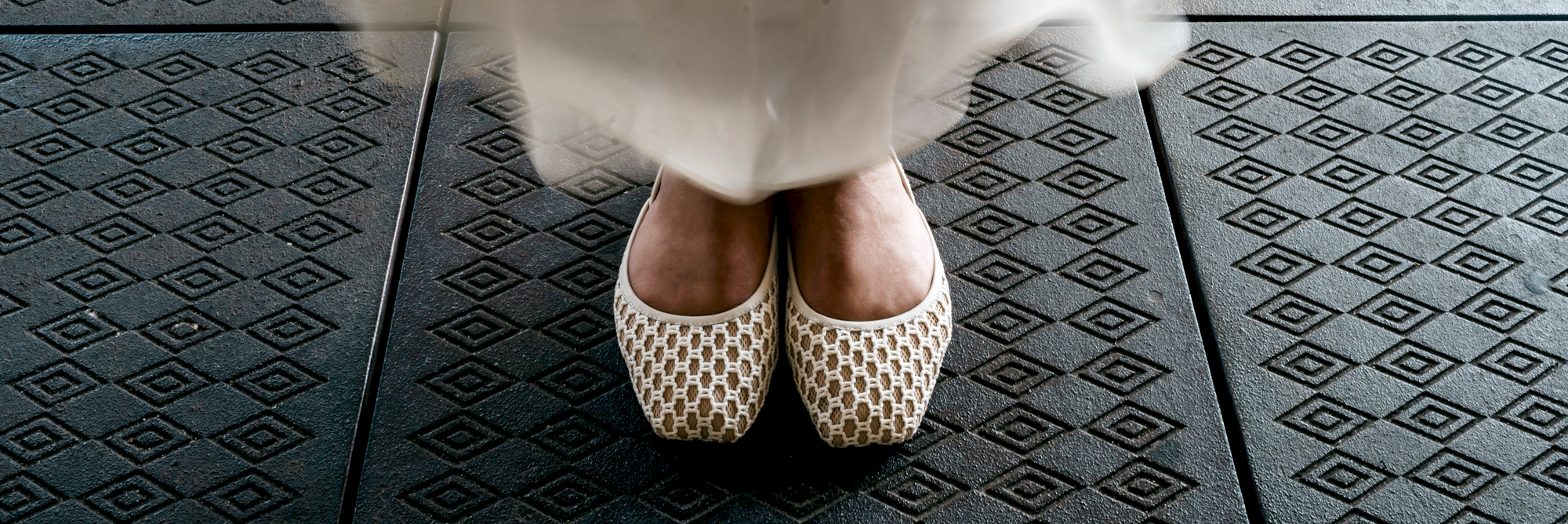 White dress with patterned shoes on a black and gray tiled floor
