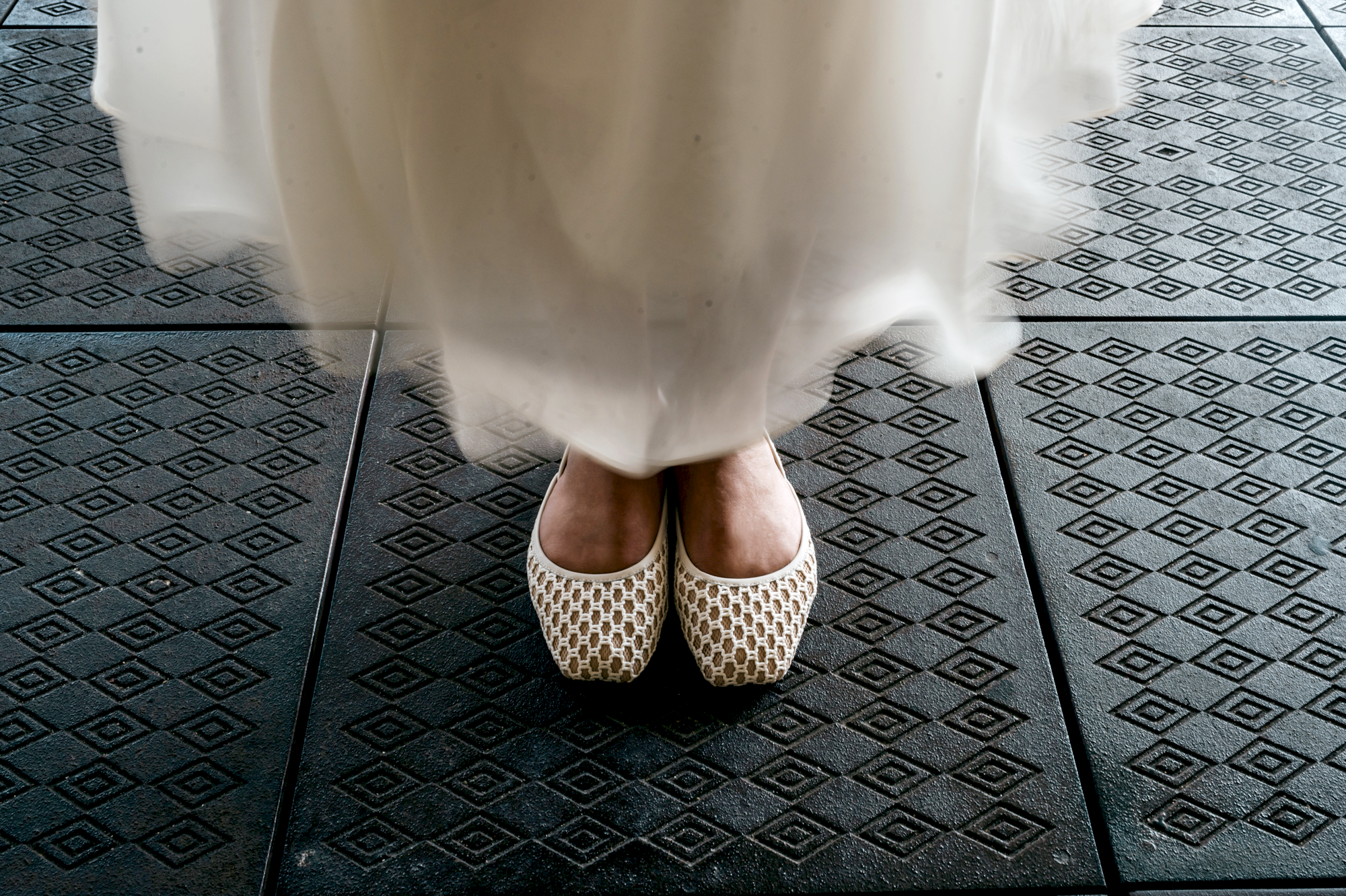 White dress with patterned flat TUAS shoes on a black and gray tiled floor