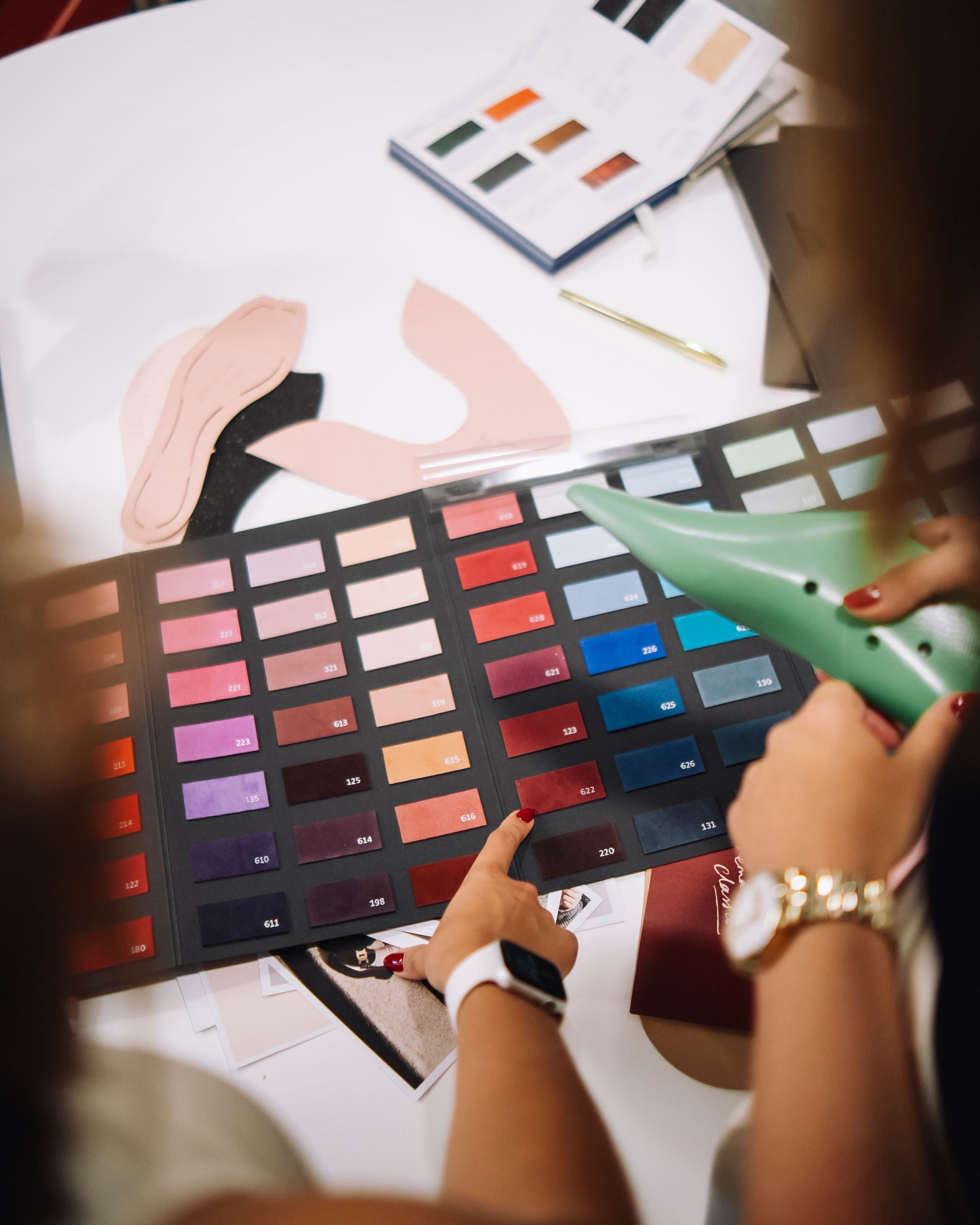Person holding a color swatch book with a palette of colors on a table.