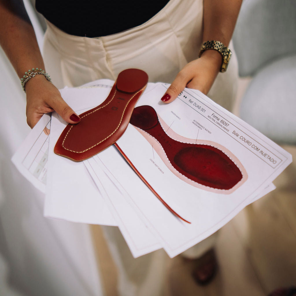 Woman holding shoe sole in her hands and sketch papers