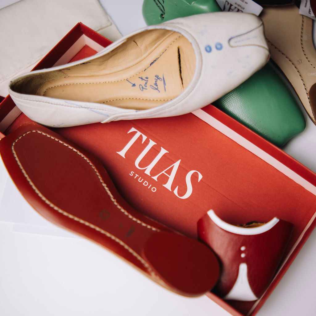 White shoe with beige interior on a red 'TUAS Studio' box
