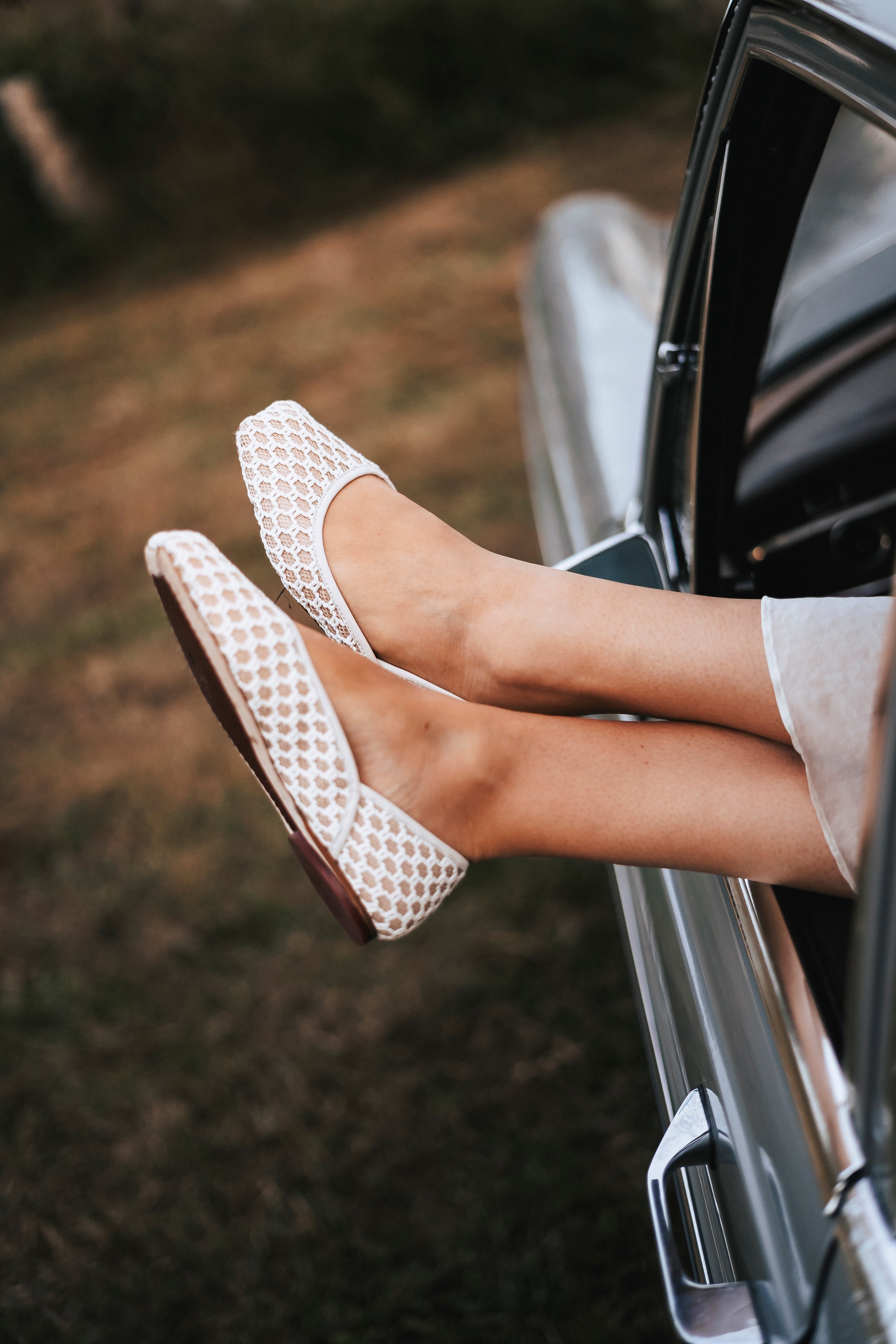 Person wearing white textured shoes stepping out of a car