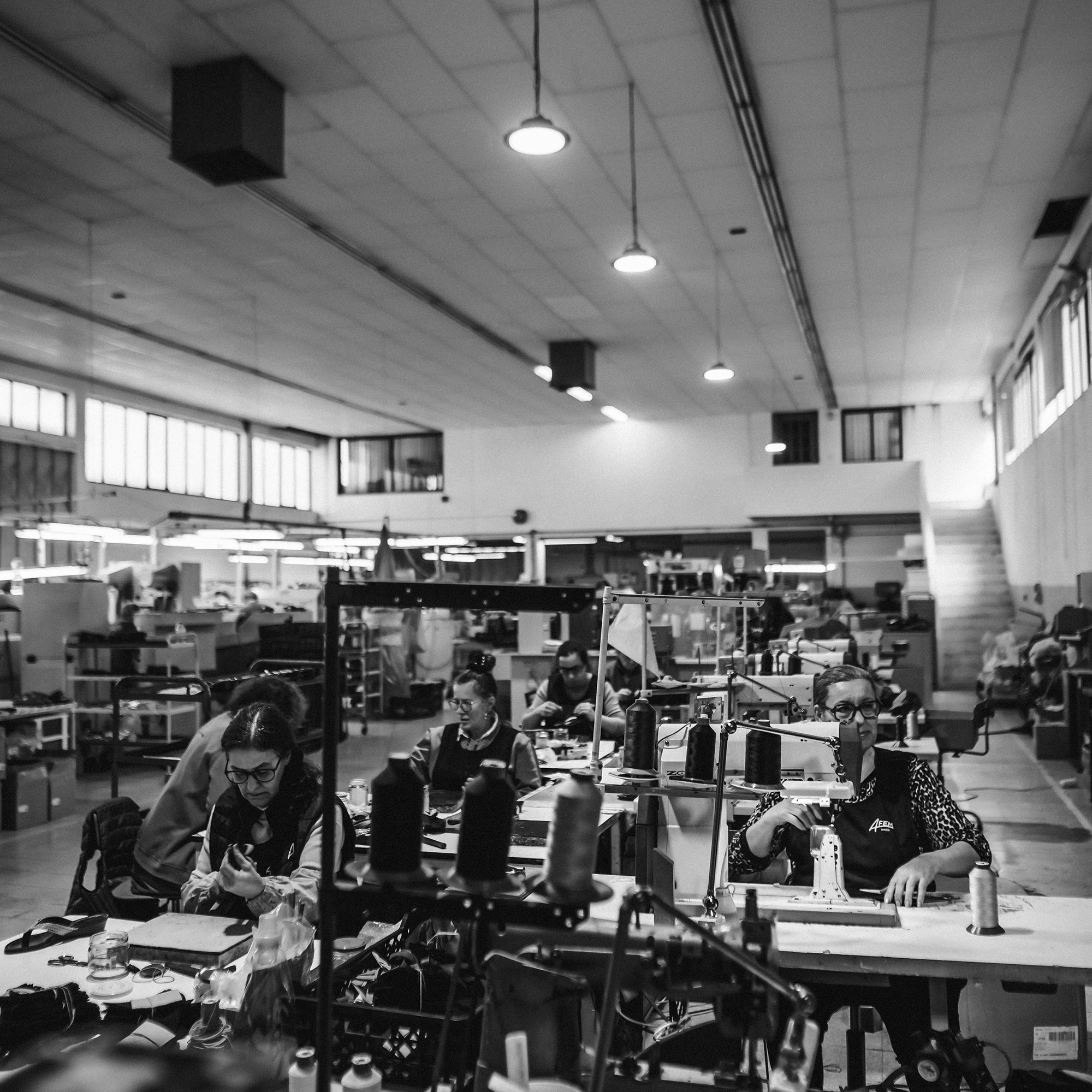Black and white photo of a busy office or factory floor with people working at desks.