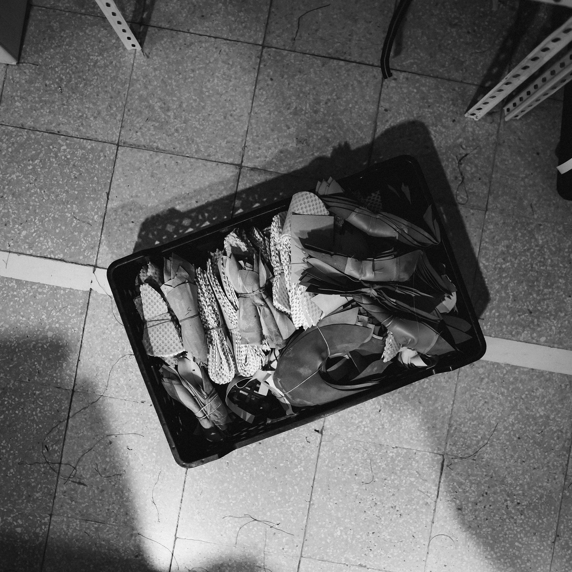 Open suitcase on a tiled floor with clothes and shoes inside