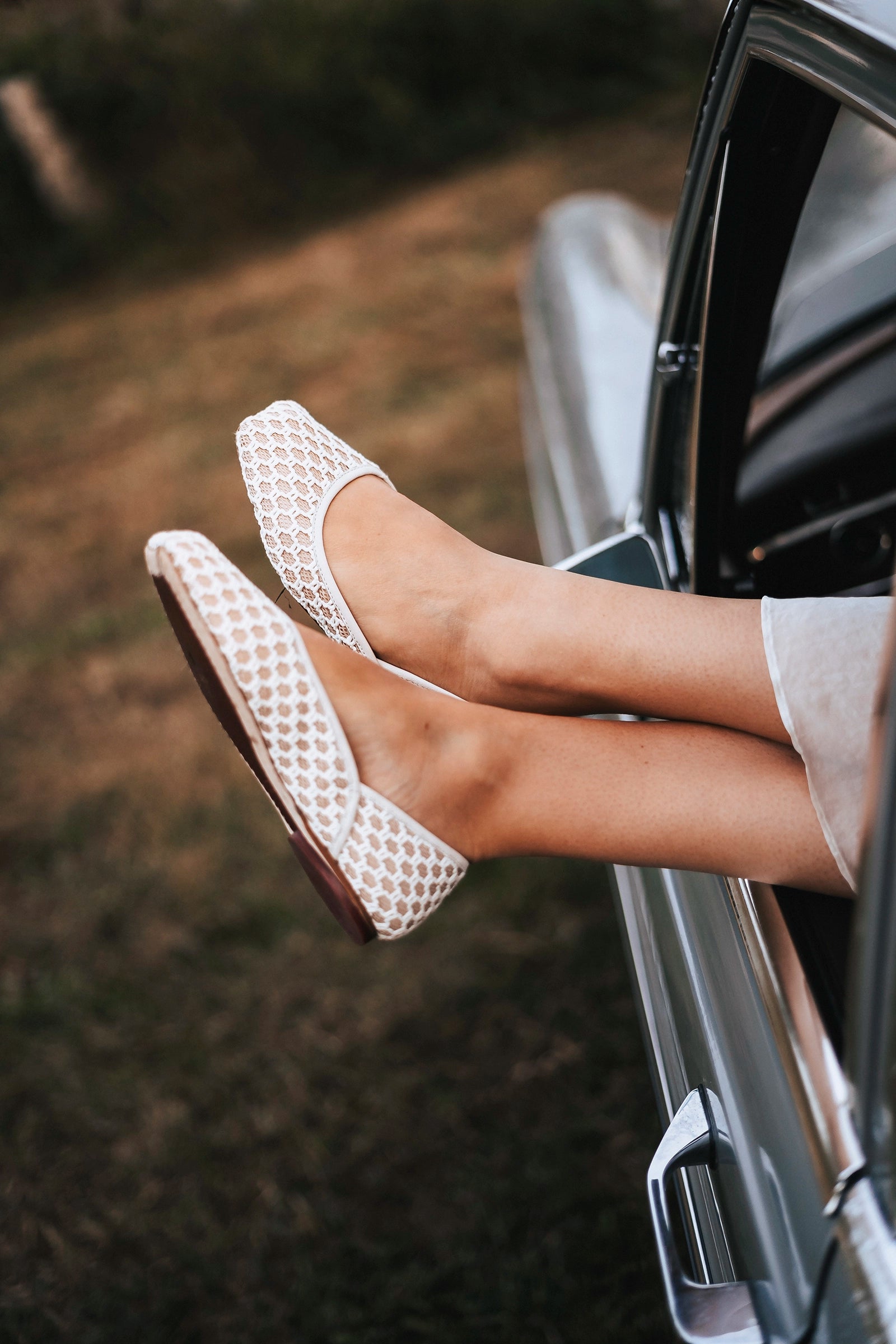 Person wearing white textured TUAS ballet flats stepping out of a car