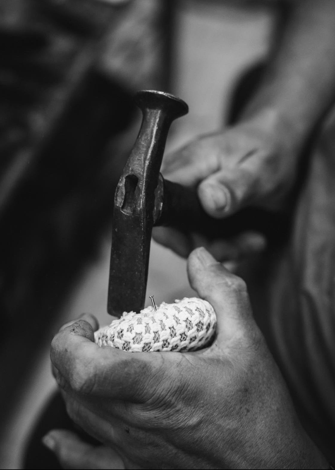 Person using a hammer on a small object with a blurred background